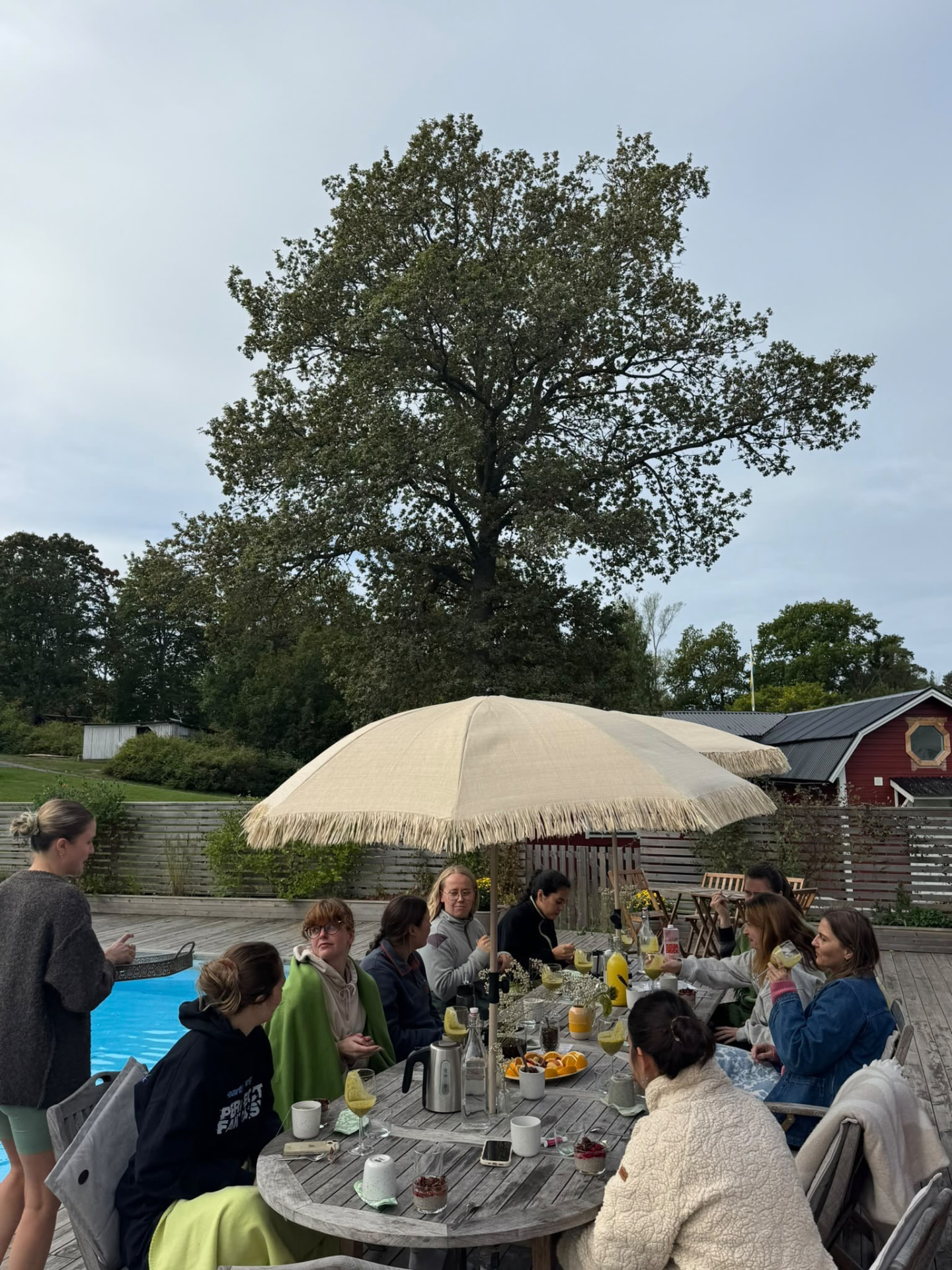 Guests sharing breakfast around the long table beside the pool